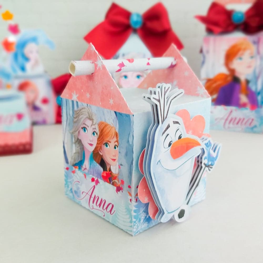 Caixa Milk do tema Frozen com telhado coral, Elsa e Anna estampadas no painel frontal e um aplique recortado em camadas do Olaf na quina da caixa, com personalização 'Anna' e laço vermelho com gema teal no topo